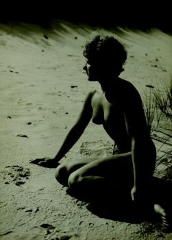 A young female kneeling on a beach A young female kneeling on a beach